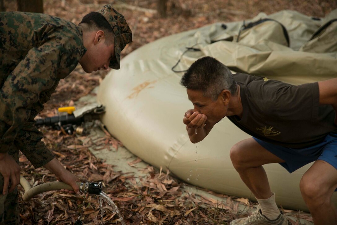 Cpl. Abraham Ostosmendoza, from Staten Island, New York, gives water to a Royal Thai Marine after his run, Feb. 11, during exercise Cobra Gold 2015 at Ban Chan Krem, Thailand. U.S. Marines utilized the Light Weight Water Purification System to clean dirty pond water and supply it to the training ranges and Thai Marines. Ostosmendoza is a water support technician with 9th Engineer Support Battalion, 3rd Marine Logistics Group, III Marine Expeditionary Force.