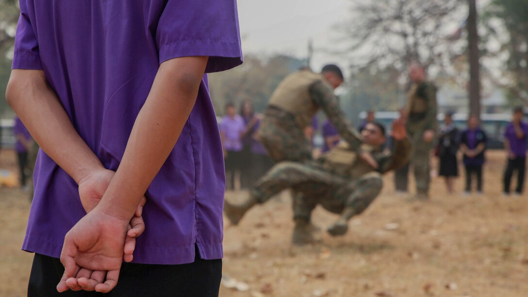 A student from Yothinnukun School watches a demonstration of Marine Corps martial arts Friendship Day held by Royal Thai Air Force Wing 1 and U.S. Marines at Royal Thai Air Force Base Korat during Exercise Cobra Gold 2015, Feb. 13. Students also observed demonstrations of Explosive Ordnance Disposal, Aircraft Rescue Firefighters, and Navy Corpsmen basic medical procedures. Cobra Gold 2015 is a Thailand /United States co-sponsored, multinational and joint theater security cooperation exercise, conducted annually in the Kingdom of Thailand, with 25 nations participating. This year there is an increased focus on Humanitarian Civic Action, community engagement, and medical activities to support the needs and humanitarian interests of civilian populations around the region. 