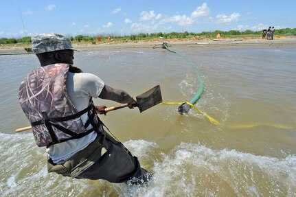 Pvt. Richard Jones of the Louisiana National Guard's 528th Engineer Battalion moves the intake pipe for a water pump that is used to inflate Tiger Dam water diversion system near the southwest pass of the Mississippi River delta May 20, 2010. The 1023rd Vertical Engineering Company is constructing an 7.1-mile barrier to prevent any possible oil from coming in to the wetlands.