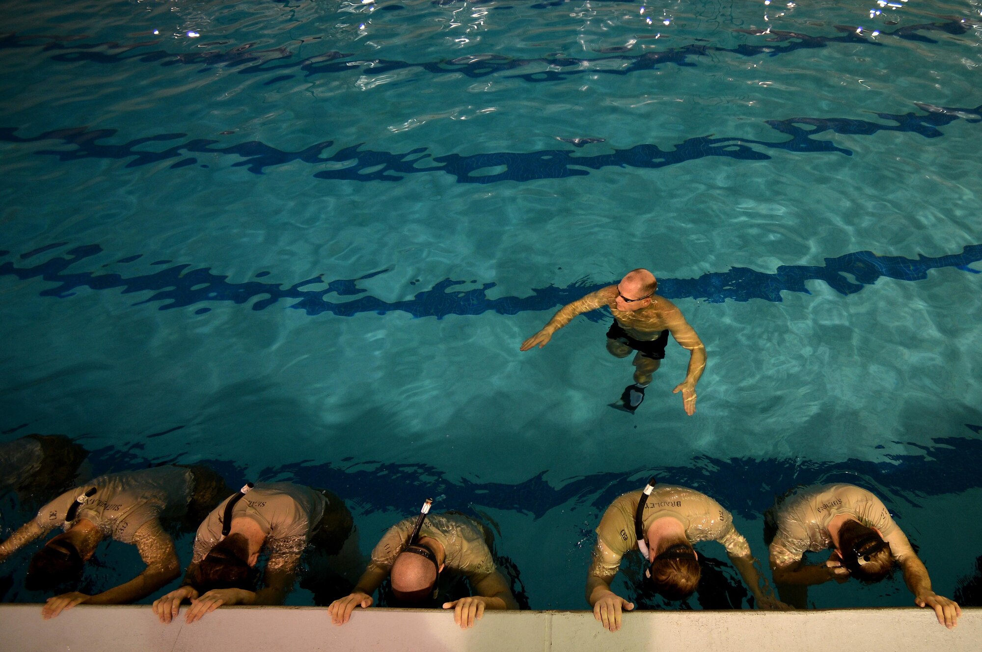 A U.S. Air Force Combat Control instructor assigned to Operating Location C, 342nd Training Squadron, (back) gives commands to CCT trainees during an early morning water circuit training session at Pope Army Airfield, North Carolina, Feb 12, 2015. CCTs among the most highly trained personnel in the U.S. military. (U.S. Air Force photo by Staff Sgt. Kenny Holston)  