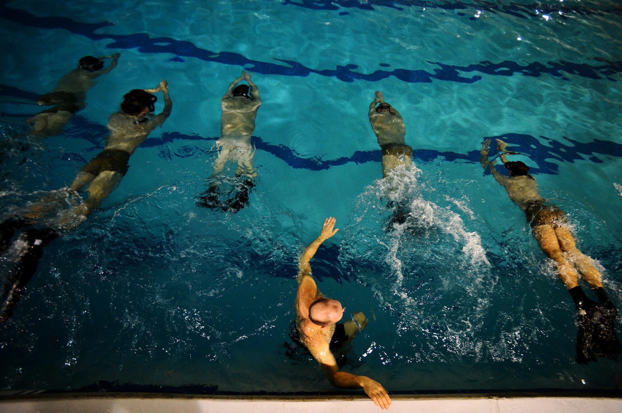 A U.S. Air Force Combat Control instructor assigned to Operating Location C, 342nd Training Squadron, (center) instructs students to begin swimming during an early morning water circuit training session at Pope Army Airfield, North Carolina, Feb 12, 2015. The students are enduring a 13 week course which will equip them with the final skills needed to be CCT or Special Operations Weather Team qualified. (U.S. Air Force photo by Staff Sgt. Kenny Holston)