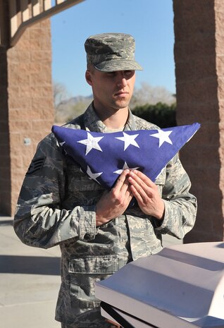 Staff Sgt. Nicholas Cocco, Nellis Air Force Base honor guardsman, practices presenting the flag during a training session at Nellis AFB, Feb. 17, 2015. The flag was folded by a six-person flag sequence and would be presented to the next of kin during a funeral service.  (U.S. Air Force photo by Airman 1st Class Rachel Loftis)