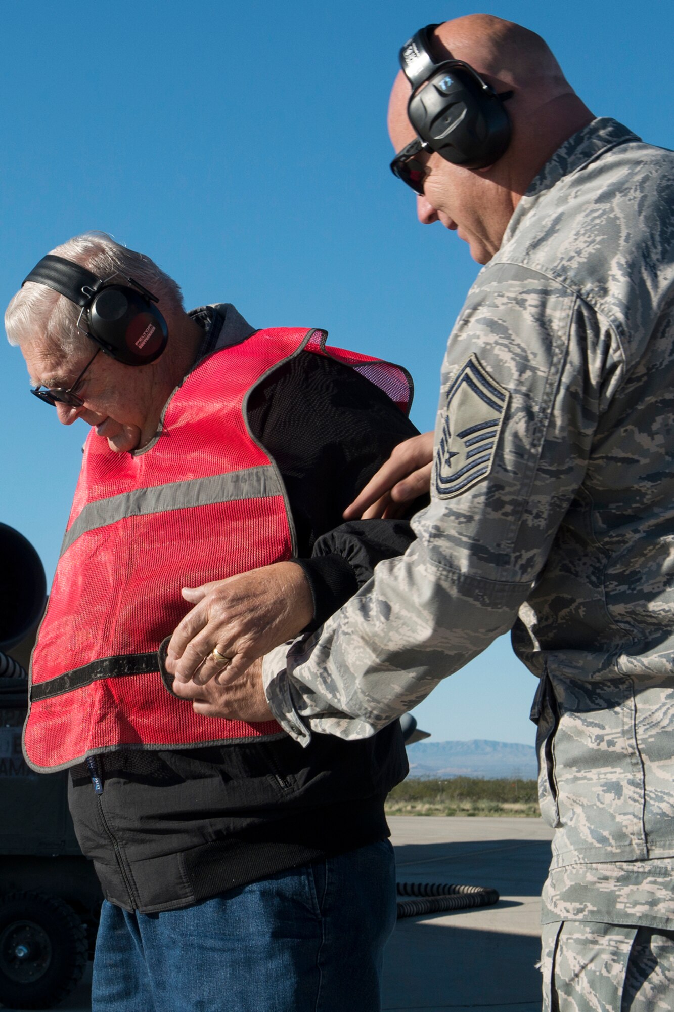 U.S. Air Force Senior Master Sgt. Gavin Smith helps Jerry Fugere put on a marshaling vest on Feb. 13, 2015, Davis-Monthan Air Force Base, Ariz. In 1962, Fugere was the first crew chief of a B-52H Stratofortress, tail number 61-007, and is given the honor of marshaling the jet from its parking spot before taking its first flight since being decommissioned in 2008. (U.S. Air Force photo by Master Sgt. Greg Steele/Released)