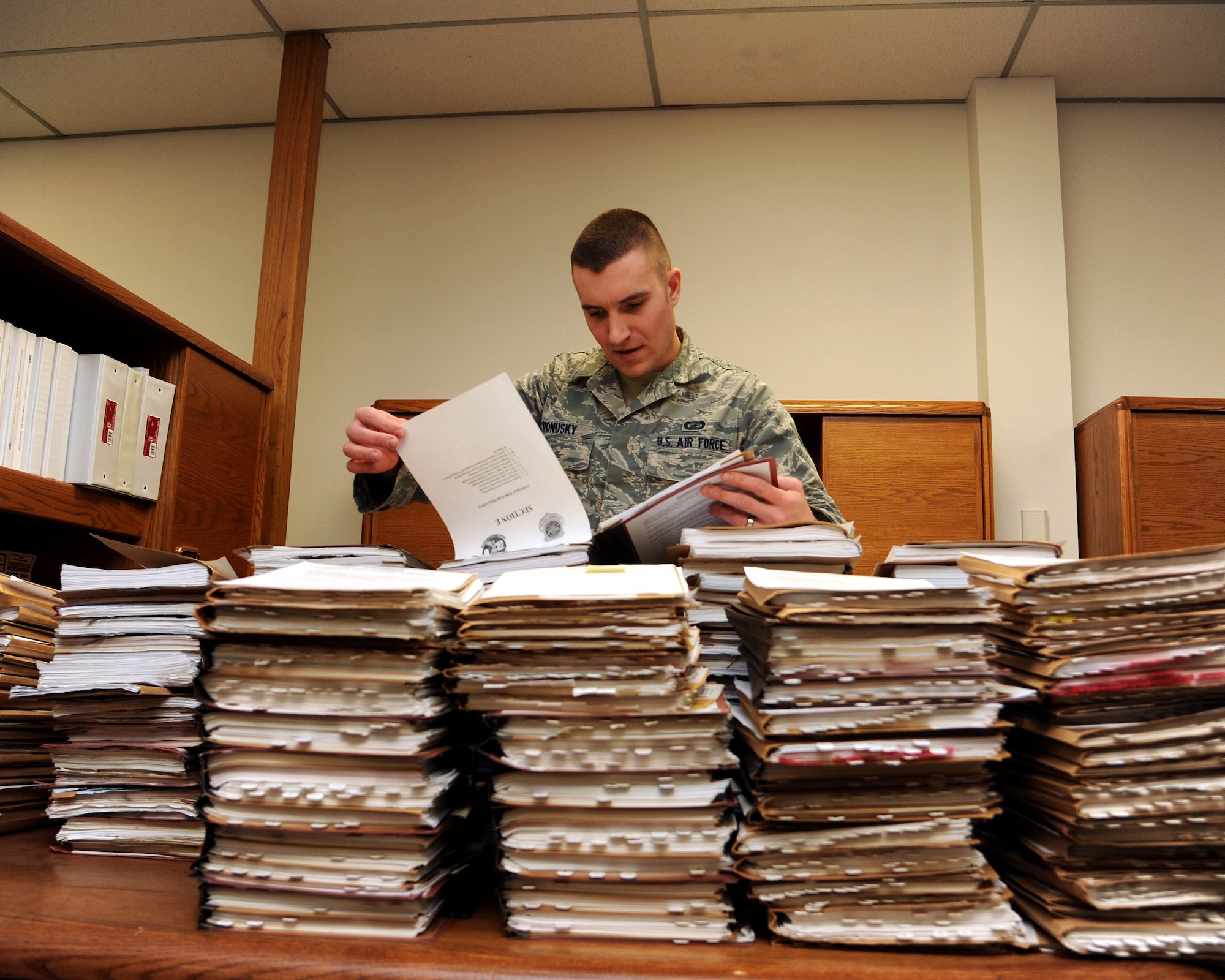 Senior Airman Alex Ponusky 319th Contracting Flight contract specialist stands amidst a mound of project files the base has completed Feb. 18, 2015 on Grand Forks Air Force Base, N.D. Ponusky responsible for all Simplified Acquisition of Base Engineering Requirements (SABER) purchases for the base (all construction projects valued under $750k). Ponusky is this week’s warrior of the week for the third week of February.(U.S. Air Force photo/Senior Airman Zachiah Roberson)