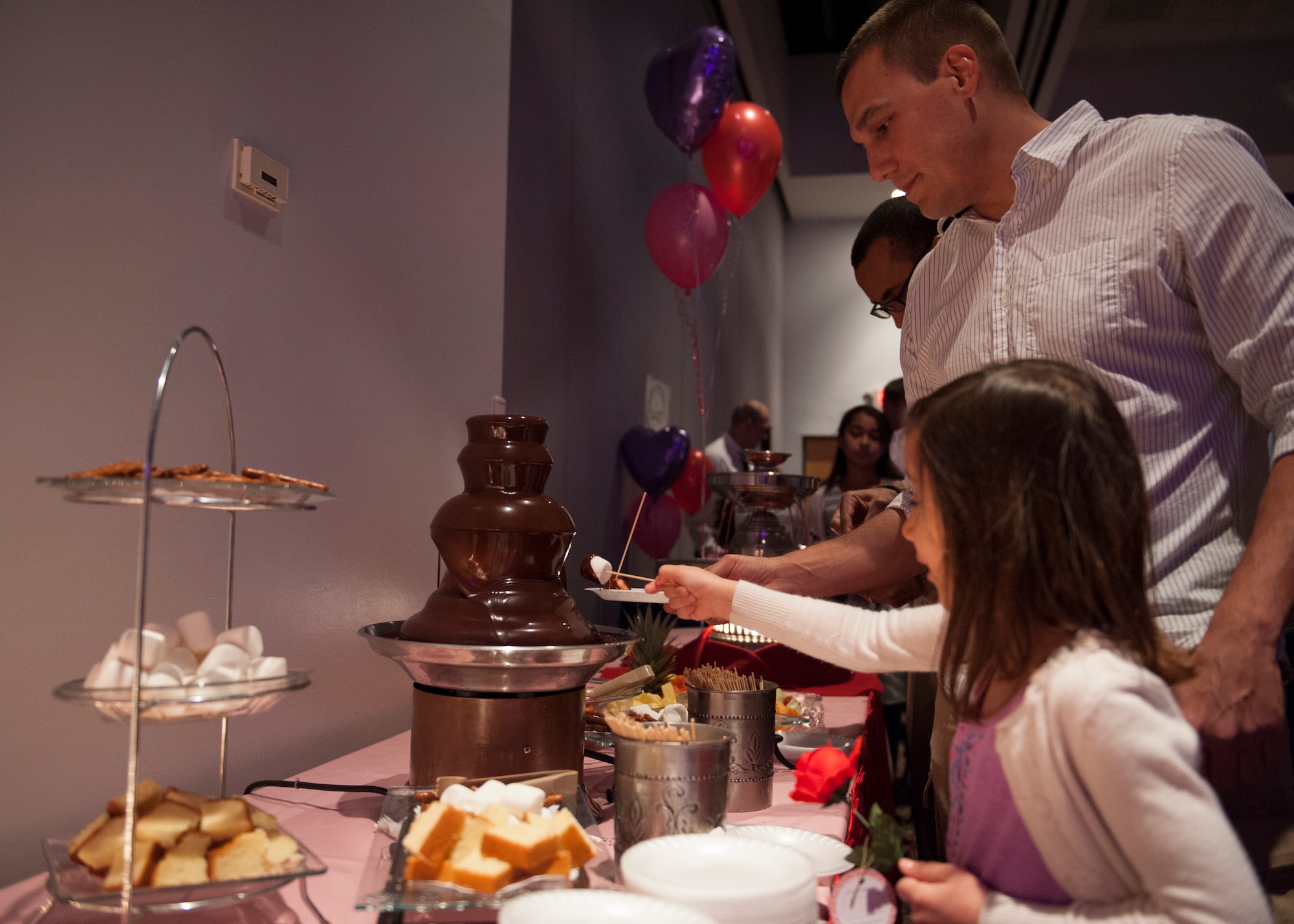 Maj. Glenn Garcia, 436th Operations Group standards and evaluations, and his daughter Isabella, 5, dip marshmallows into a chocolate fountain Feb. 13, 2015, at the Landings Club on Dover Air Force Base, Del. The event featured an assortment of pastries. (U.S. Air Force photo/Airman 1st Class Zachary Cacicia)