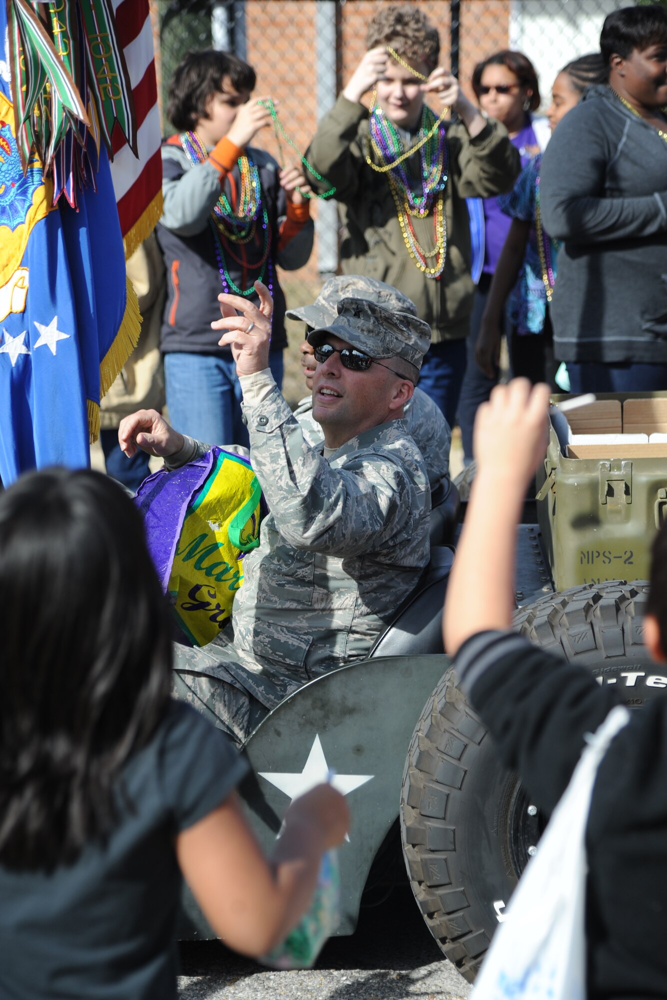Brig. Gen. Patrick Higby, 81st Training Wing commander, and Chief Master Sgt. Harry Hutchinson, 81st TRW command chief, throw beads into the crowd during the Jeff Davis Elementary School Mardi Gras Parade in Biloxi, Miss., Feb. 13, 2015. Higby and Hutchinson served as Grand Marshalls for the event. (U.S. Air Force photo by Kemberly Groue)