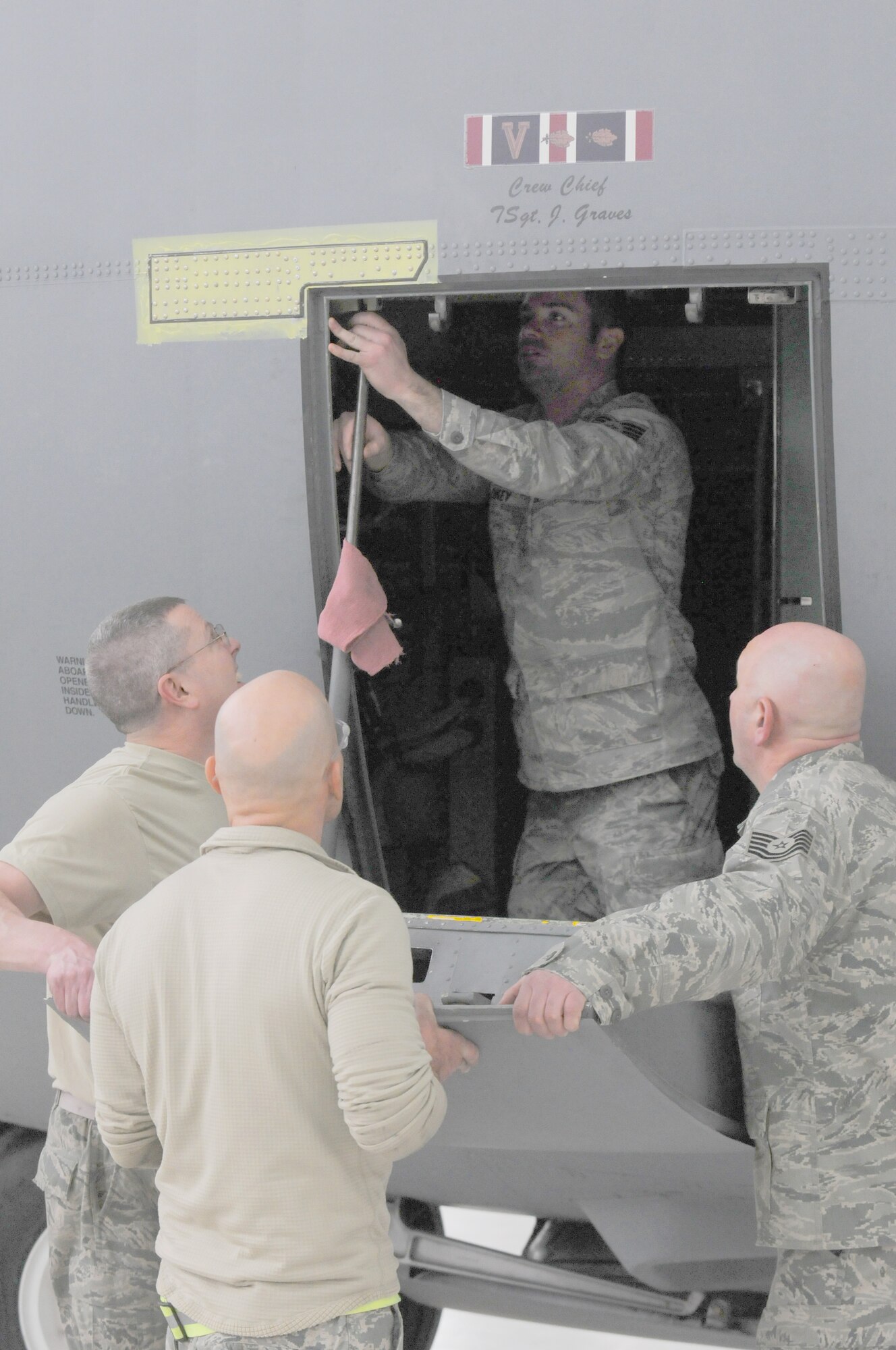 Staff Sgt. Derek Saros, Tech. Sgt. Chris Tenny and Staff Sgt. Scott Clokey, all assigned to the 910th Maintenance Group's Repair and Reclamation shop, along with Chief Master Sgt. Jim Graves, crew chief, re-attach the crew door on a C-130H Hercules aircraft here, Feb. 7, 2015. Maintainers repaired a crack just above the entryway. U.S. Air Force photo/Tech. Sgt. James Brock.