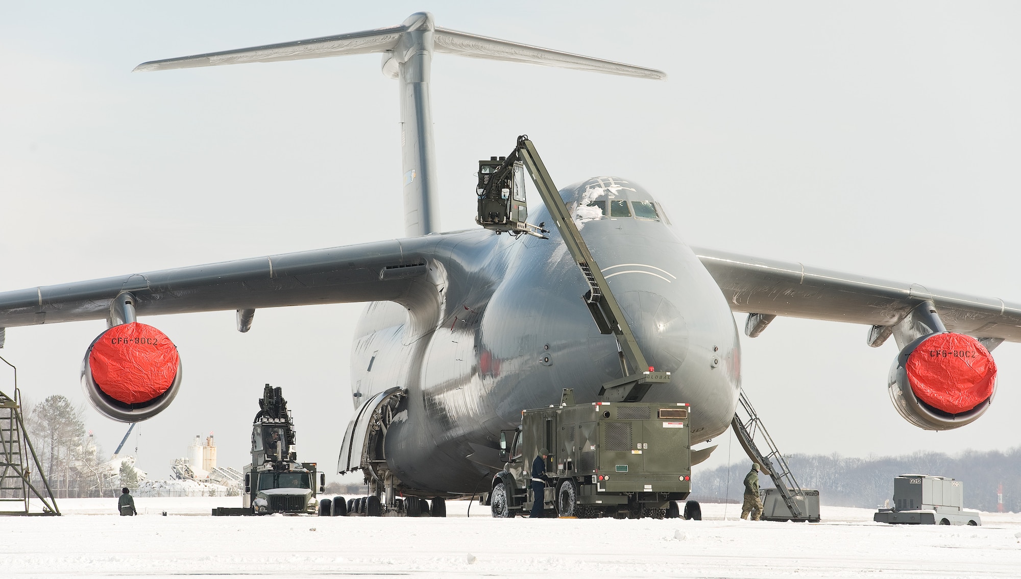 Personnel from the 436th Aircraft Maintenance Squadron remove snow and ice from a C-5M Super Galaxy Feb. 17, 2015, on Dover Air Force Base, Del. Maintenance personnel used deicing vehicles to remove four inches of snow that covered aircraft parked on the flight line. (U.S. Air Force photo/Roland Balik)