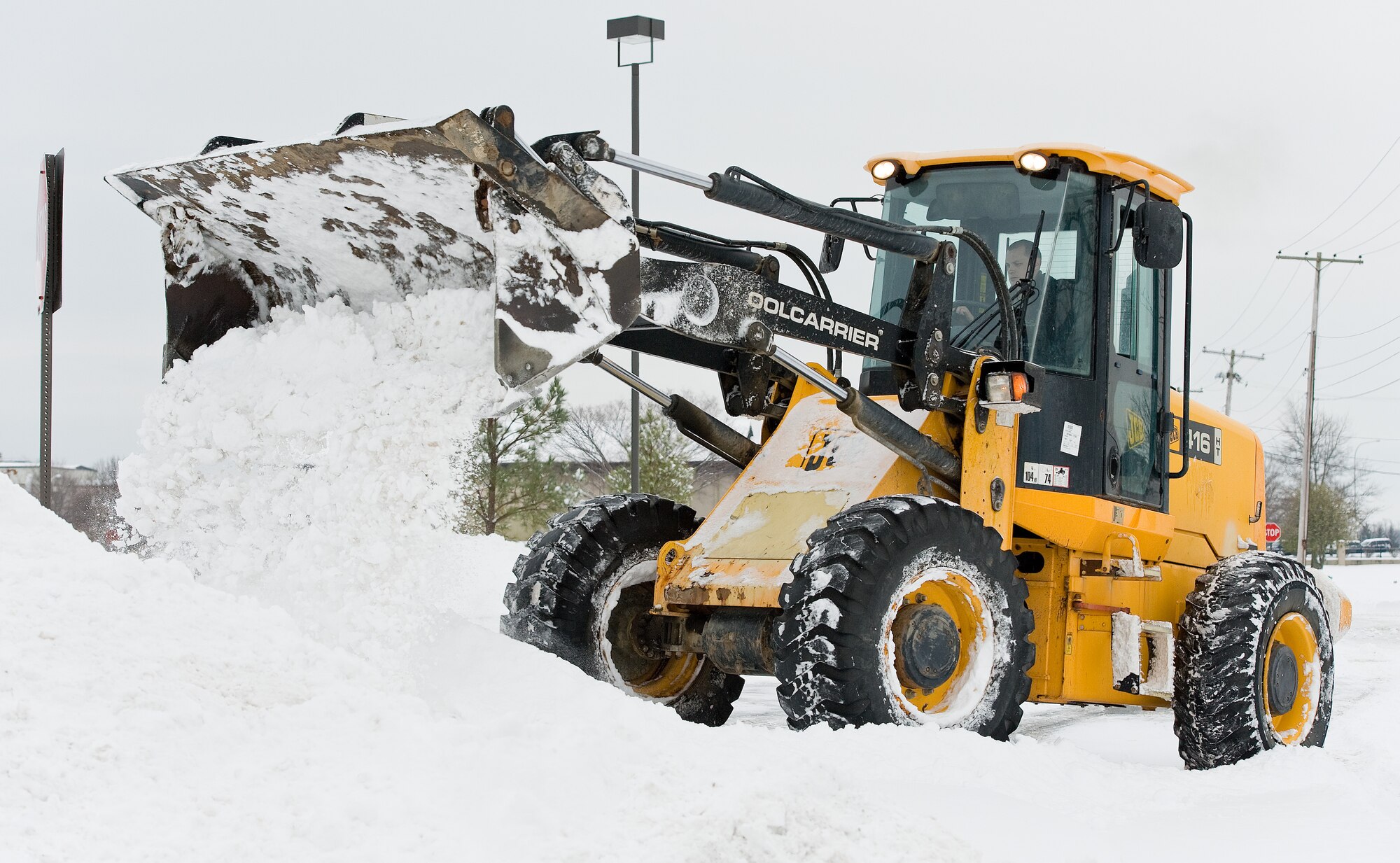 Staff Sgt. Mitchell Scott, from the 436th Civil Engineer Squadron Utilities shop, clears snow from the road Feb. 17, 2015, near the base gas station on Dover Air Force Base, Del. Scott and other 436th CES members cleared snow from roads, parking lots, flight line, runways and taxiways after quick moving Winter Storm Octavia passed through the Dover area. (U.S. Air Force photo/Roland Balik)