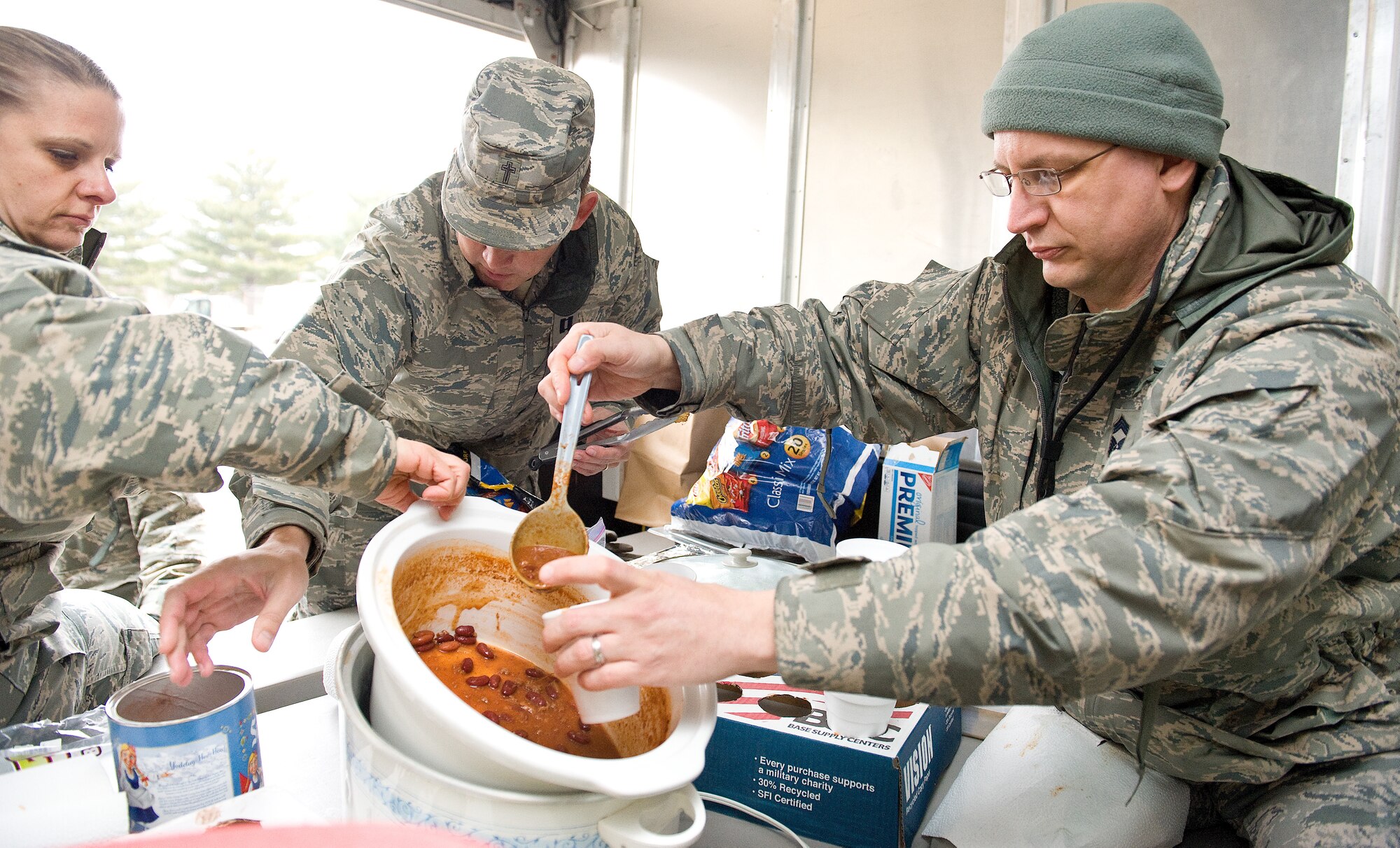Chief Master Sgt. Sandra Scott, 436th Aerial Port Squadron ground terminal manager, left; Chaplain (Capt.) Quentin Genke, 436th Airlift Wing, center; and Chief Master Sgt. Dennis Tauchus, 436th Aircraft Maintenance Squadron superintendent, right, fill cups of homemade chili Feb. 9, 2015, on Dover Air Force Base, Del. On Feb. 8-9, the Dover Chief's Group visited numerous facilities on the base and passed out cups of hot cocoa, chili and other food items to over 600 Team Dover members. (U.S. Air Force photo/Roland Balik)