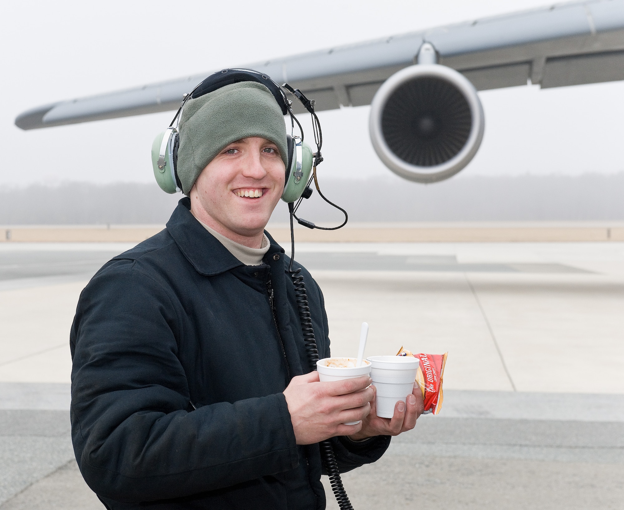 Senior Airman Michael Gerken, 436th Aircraft Maintenance Squadron crew chief, walks back to a C-5M Super Galaxy with hot cocoa and chili Feb. 9, 2015, on Dover Air Force Base, Del. The Dover Chief's Group made stops at C-5M and C-17A aircraft parked on the flight line and passed out cups of hot cocoa, homemade chili and other food items to Team Dover maintainers during Operation Cocoa and Chili. (U.S. Air Force photo/Roland Balik)