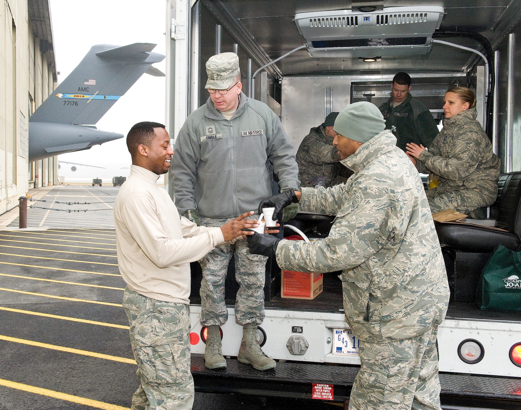 Chief Master Sgt. Darryl Ross, 436th Force Support Squadron superintendent, right, hands a cup of homemade chili to Staff Sgt. Christopher Smith, 736th Aircraft Maintenance Squadron home station check team member, left, Feb. 9, 2015, on Dover Air Force Base, Del. Ross, Senior Master Sgt. John Tingle, 436th Civil Engineer Squadron superintendent, center; Chief Master Sgts. Sandra Scott, 436th Aerial Port Squadron ground terminal manager, sitting right; Nolan Massaroni, 436th Maintenance Operations superintendent; and Dennis Tauchus, 436th Aircraft Maintenance Squadron superintendent, stopped at an aircraft maintenance hangar and passed out cups of hot cocoa, homemade chili and other food items. (U.S. Air Force photo/Roland Balik)