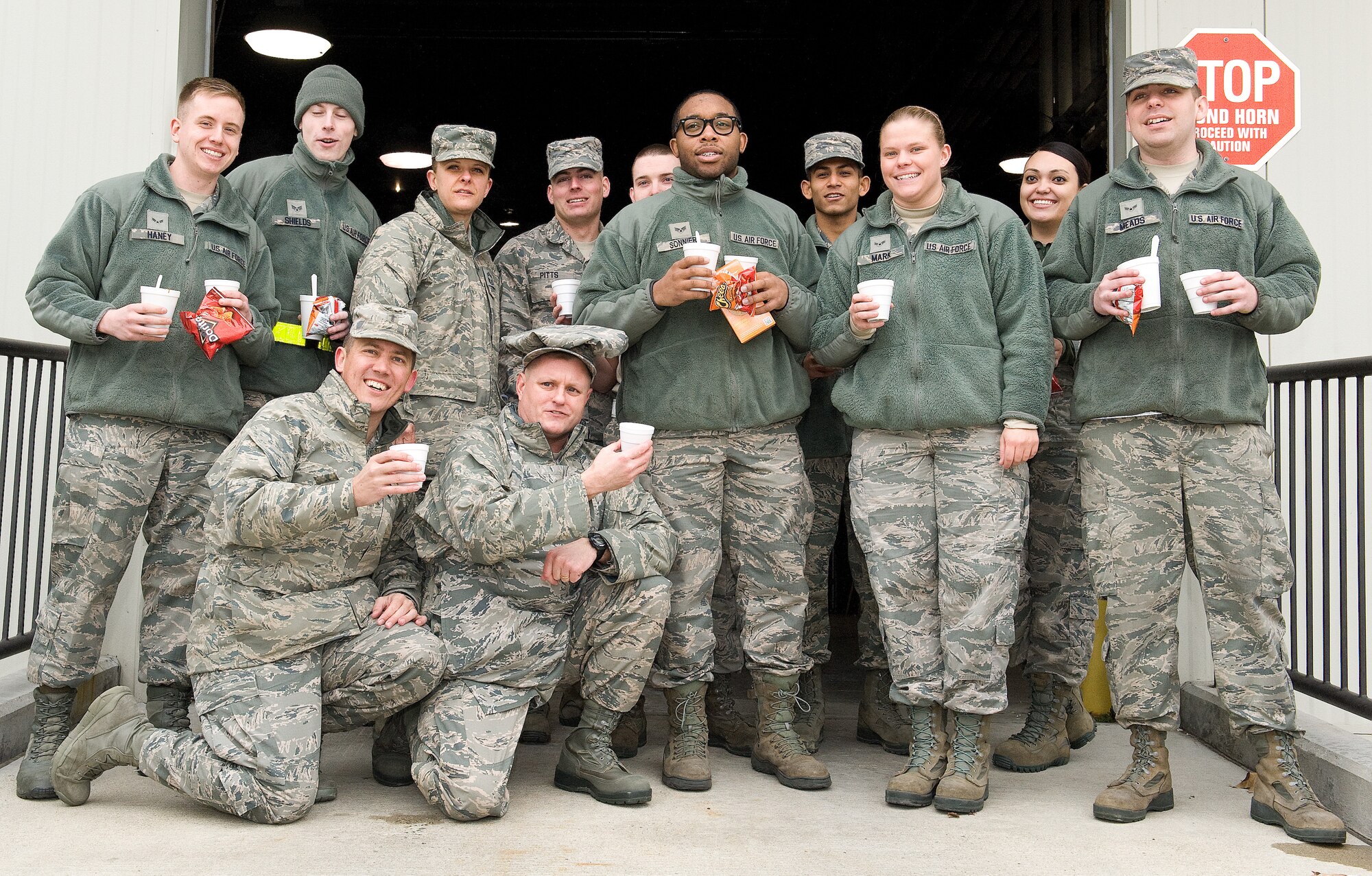 Chaplain (Capt.) Quentin Genke, 436th Airlift Wing, kneeling left, and Chief Master Sgt. John Elstrom, 436th Maintenance Group superintendent, kneeling second from left, pose for a photo with members of the 436th Aerial Port Squadron Feb. 9, 2015, on Dover Air Force Base, Del. The Dover Chief's Group passed out cups of hot cocoa, homemade chili and other food items to members of the Super Port. (U.S. Air Force photo/Roland Balik)