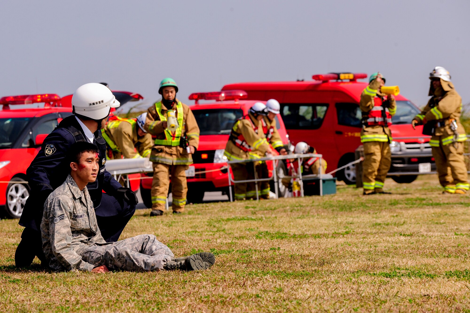 U.S. Air Force Senior Airman Suriyun Soukhamneut, 18th Component Maintenance Squadron aerospace propulsion journeyman, receives medical care from an Airman and a Nirai Fire Department paramedic on Torii Station, Japan, Feb. 17, 2015. The annual exercise was held to test and improve the communication and proficiency between U.S. and Japanese agencies when responding to an emergency scenario. (U.S. Air Force photo by Airman 1st Class John Linzmeier)