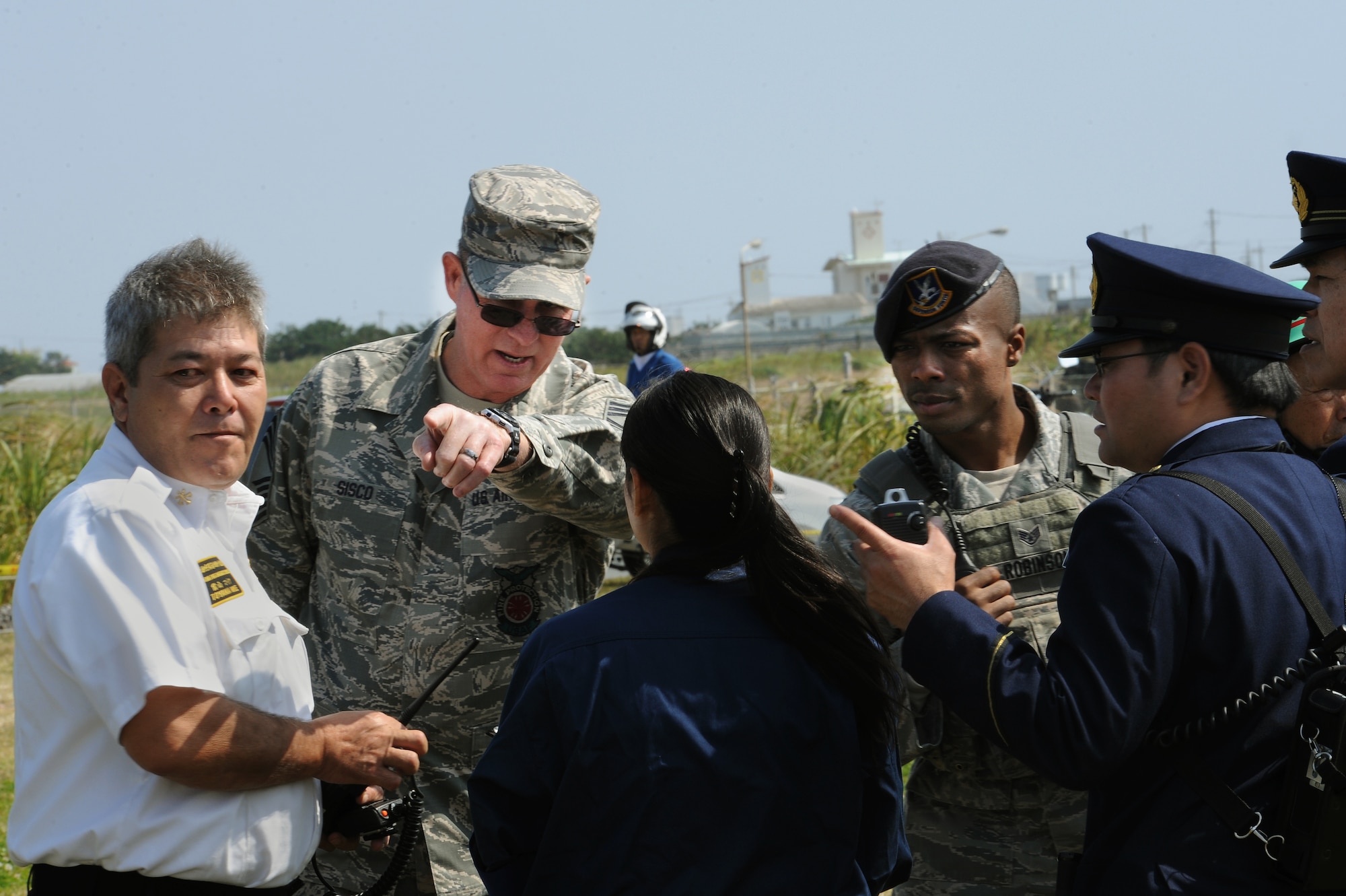 Mike Toyama, 18th Civil Engineer Squadron fire and emergency services master labor contract chief, and U.S. Air Force Chief Master Sgt. Albert Sisco, Jr., 18th CES fire and emergency services department chief, speak with leaders from local emergency services agencies during a bilateral aircraft mishap exercise on Torii Station, Japan, Feb. 17, 2015. The annual exercise is intended to enhance coordination between U.S. military first responders, their local counterparts and other local and U.S. government agencies. (U.S. Air Force photo by Airman 1st Class Zade C. Vadnais)