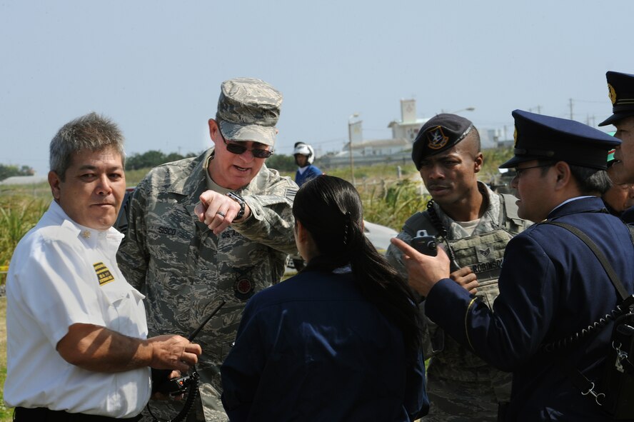 Mike Toyama, 18th Civil Engineer Squadron fire and emergency services master labor contract chief, and U.S. Air Force Chief Master Sgt. Albert Sisco, Jr., 18th CES fire and emergency services department chief, speak with leaders from local emergency services agencies during a bilateral aircraft mishap exercise on Torii Station, Japan, Feb. 17, 2015. The annual exercise is intended to enhance coordination between U.S. military first responders, their local counterparts and other local and U.S. government agencies. (U.S. Air Force photo by Airman 1st Class Zade C. Vadnais)