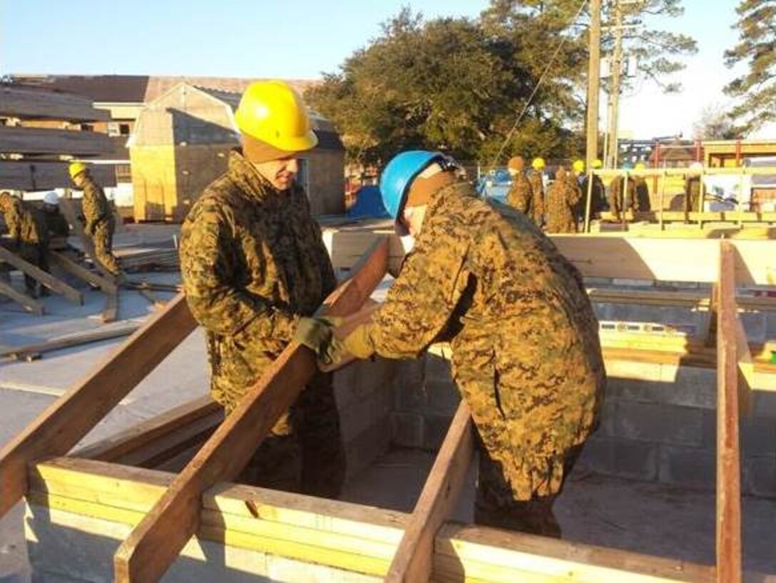 Marines of BCE10-15 build a wood frame for a roof on a building.