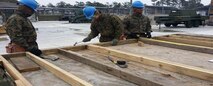 Marines make measurements for a wall during wood frame construction.