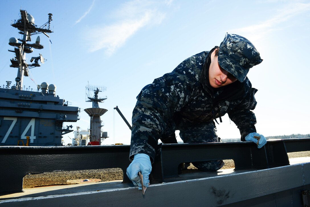 Navy Seaman Lauren Lindhout sands an angle iron on the flight deck of the USS John C. Stennis in Bremerton, Wash., Feb. 17, 2015. Lindhout is an aviation boatswain's mate airman