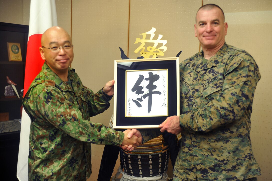 Japanese Warrant Officer Yoshiaki Suzuki, left, Ground Self-Defense Force sergeant major, presents a gift to U.S. Marine Corps Sgt. Maj. Bryan Battaglia, senior enlisted advisor to the chairman of the Joint Chiefs of Staff, during a meeting on Camp Ichigaya in Tokyo, Japan, Feb. 10.