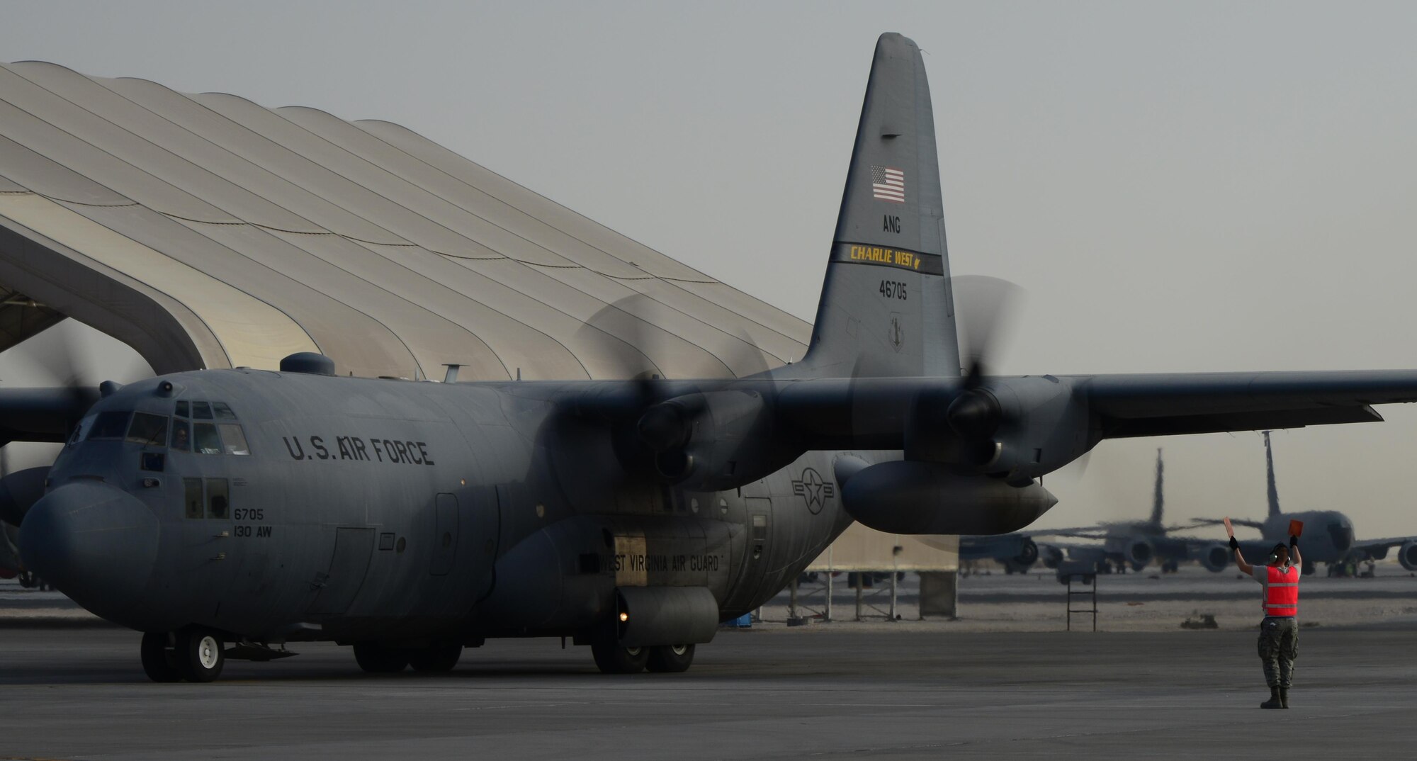 U.S. Air Force Airman 1st Class Evin Hamm, 746th Expeditionary Aircraft Maintenance Unit crew chief, marshals a C-130 Hercules out of its parking spot, Feb. 18, 2015, at Al Udeid Air Base, Qatar. The current Hercules maintenance team is comprised of Air National Guard Units deployed from 130th Airlift Wing out of Charleston, W. Va., and the 153rd Airlift Wing out of Cheyenne, Wyo. As a unit, they inspect, service and prepare aircraft for the mission of the day as delegated by the air tasking order and ensure the C-130s are mission capable by performing regular inspections and preventative and scheduled maintenance. (U.S. Air Force photo by Senior Airman Kia Atkins)