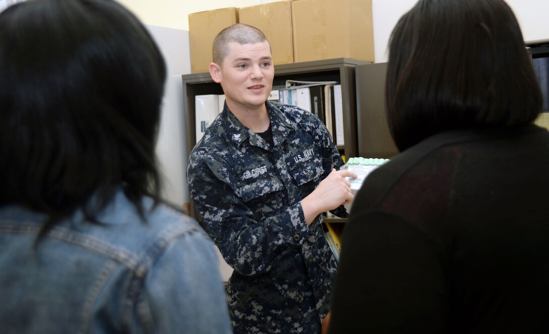 HM3 Nicholas Gilchrist, laboratory technician, Naval Branch Health Clinic, Albany, explains the process of using blood collection tubes to two Dougherty County high school students, Feb. 18. The students were part of a group who shadowed specialists in various occupations around Marine Corps Logistics Base Albany. 