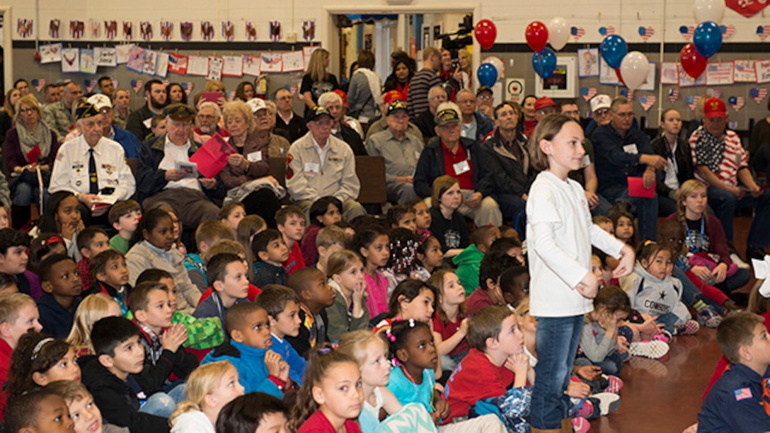 Survivors from the battle of Iwo Jima and students at Sheppard Air Force Base Elementary School listen to a special program perfomed for survivors of the battle of Iwo Jima during the 70th Iwo Jima Veteran's Program by the Sheppard Choir at Sheppard Air Force Base, Texas, February 13, 2015. Students sang special songs for the event and sixth grade students read poems they wrote for the occasion.