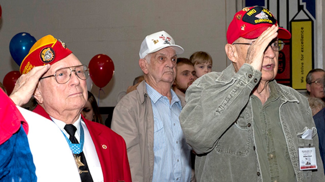 Hershel "Woody" Williams, Marine survivor from the battle of Iwo Jima and the last living Medal of Honor recipient for his actions during the battle, and William "Bil" Schott a Marine survivor from the battle of Iwo Jima, salute during the singing of the Star Spangled Banner during the 70th Anniversary Iwo Jima Veteran's Program at Sheppard Air Force Base Elementary School, Sheppard Air Force Base, Texas, February 13, 2015. The students at the school performed a program with the Sheppard Choir singing songs and the sixth graders reading poems they wrote.