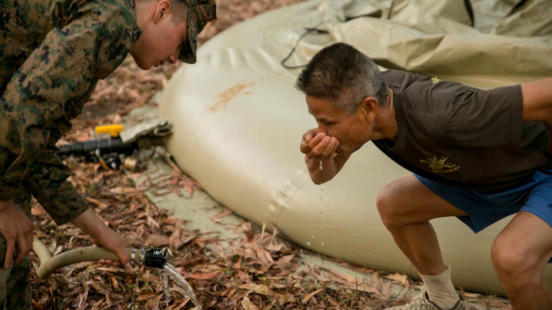 Cpl. Abraham Ostosmendoza, from Staten Island, New York, gives water to a Royal Thai Marine after his run, Feb. 11, during exercise Cobra Gold 2015 at Ban Chan Krem, Thailand. U.S. Marines utilized the Light Weight Water Purification System to clean dirty pond water and supply it to the training ranges and Thai Marines. Ostosmendoza is a water support technician with 9th Engineer Support Battalion, 3rd Marine Logistics Group, III Marine Expeditionary Force.