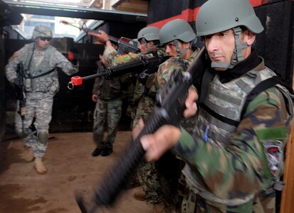 Working with Minnesota National Guard Soldiers, Afghan National Army soldiers prepare to clear a room during an Operational Mentoring and Liaison Team training exercise at the Joint Multinational Readiness Center in Hohenfels, Germany. Sixty-five Afghan soldiers participated in OMLT training at JMRC to help prepare U.S. and multinational troops to deploy to Afghanistan as part of the NATO International Security Assistance Force. The OMLT will help with the ISAF mission of assisting the government of Afghanistan in establishing and maintaining a safe and secure environment.