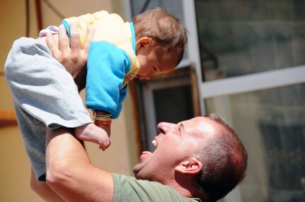 Staff Sgt. Peter Ladensack, a member of the Vermont National Guard's 86th Infantry Brigade Combat Team, plays with a baby during a visit to an orphanage in Bamyan province, May 26, 2010. The Soldier is part of the Delaware Embedded Training Team, which along with the New Zealand Provincial Reconstruction Team delivered and assembled bunk beds for the orphanage and gave out clothing, toys and stuffed animals to the kids.