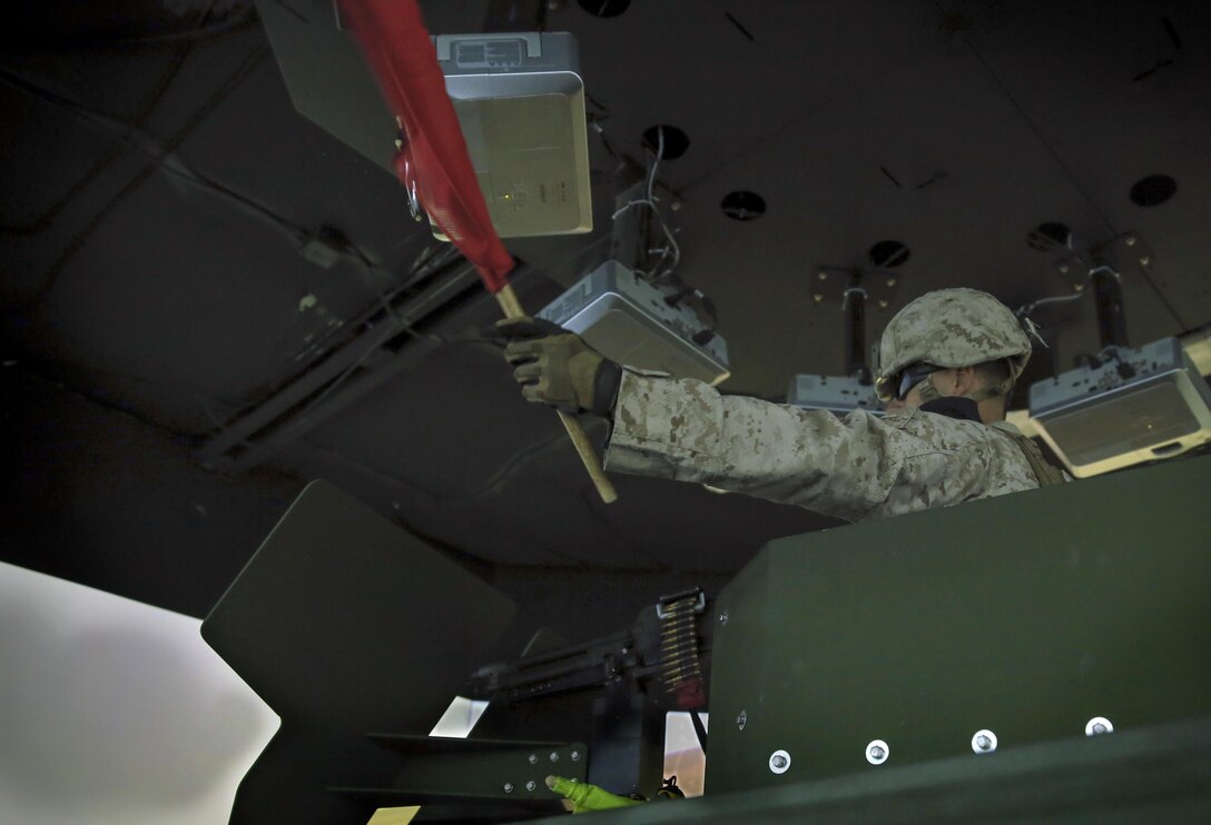 Lance Cpl. Joshua Robinett, security forces, Company C, Marine Wing Support Squadron 371, uses a signal flag to halt a simulated bystander while training in the Combat Convoy Simulator at Camp Wilson, Feb. 11, 2015. The Marines handled events in real time while following the Standard Operating Procedures they will use when the unit deploys. (Official Marine Corps photo by Lance Cpl. Thomas Mudd/ Released)