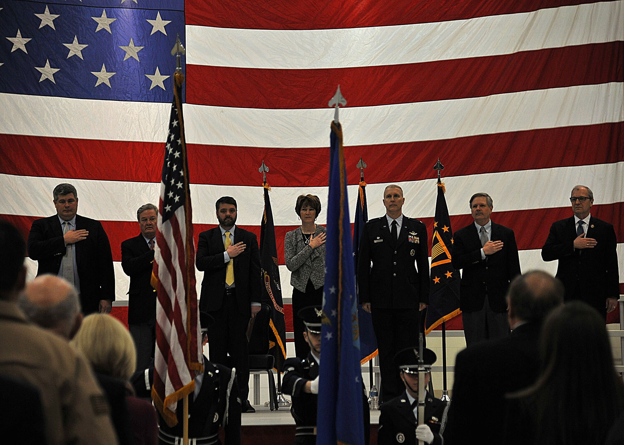 Distinguished visitors render courtesies during the playing of the national anthem during the Grand Sky Enhanced Use Lease signing event on Feb. 18, 2015 on Grand Forks Air Force Base, N.D. The Air Force is leasing 217 acres of non-excess land on Grand Forks AFB and the project is estimated to produce 3,000 local jobs. (U.S. Air Force photo/Senior Airman Xavier Navarro)