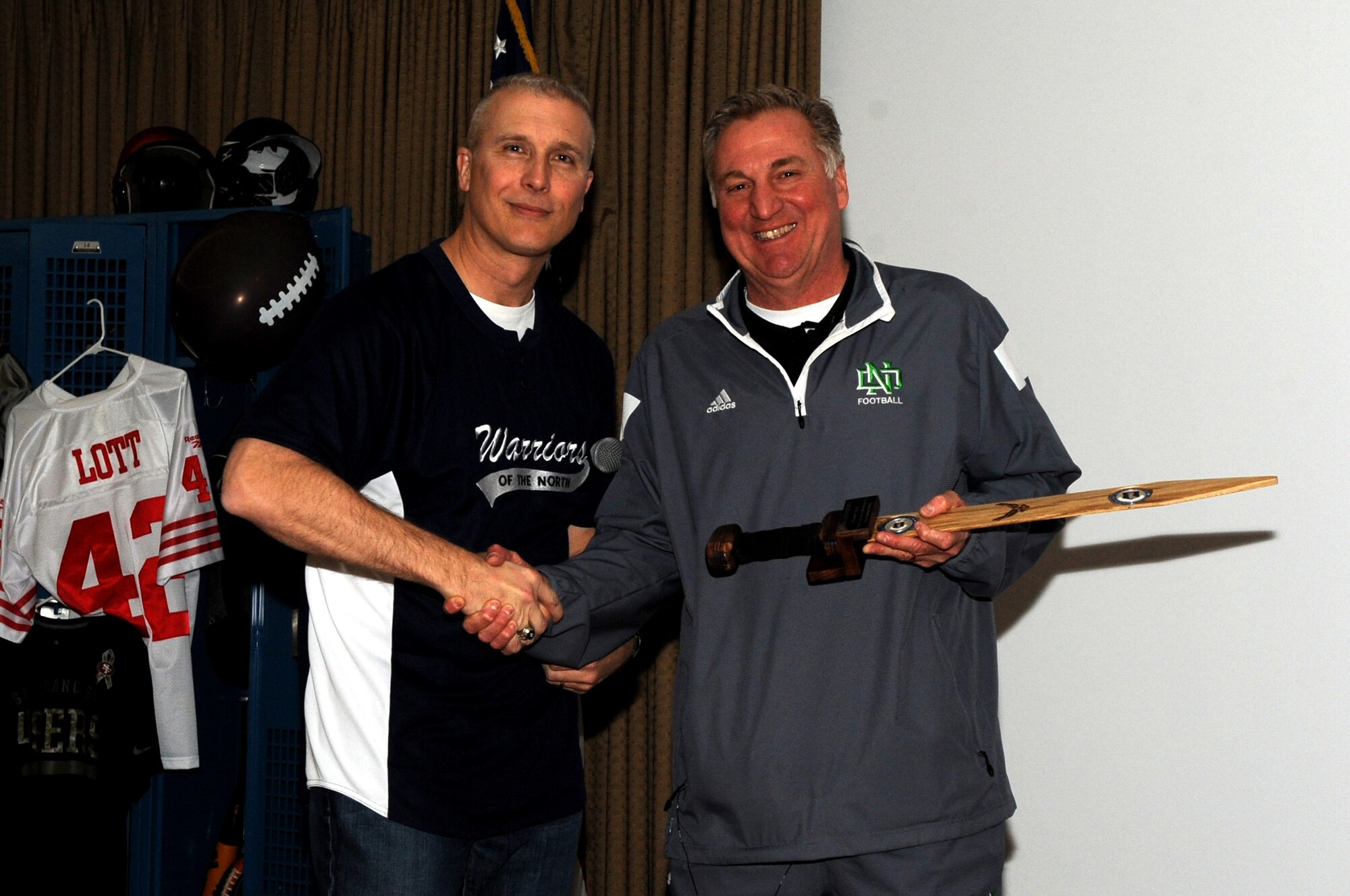 Col. Paul Bauman, 319th Air Base Wing commander, presents a memento to Kyle "Bubba" Schweigert, head coach of University of North Dakota football, who was the guest speaker at the Grand Forks Air Force Base Annual Awards Ceremony at the Northern Lights Club, Feb. 6, 2015. The event kept the new tradition established last year with its sports theme. (U.S. Air Force photo/Staff Sgt. Susan L. Davis)