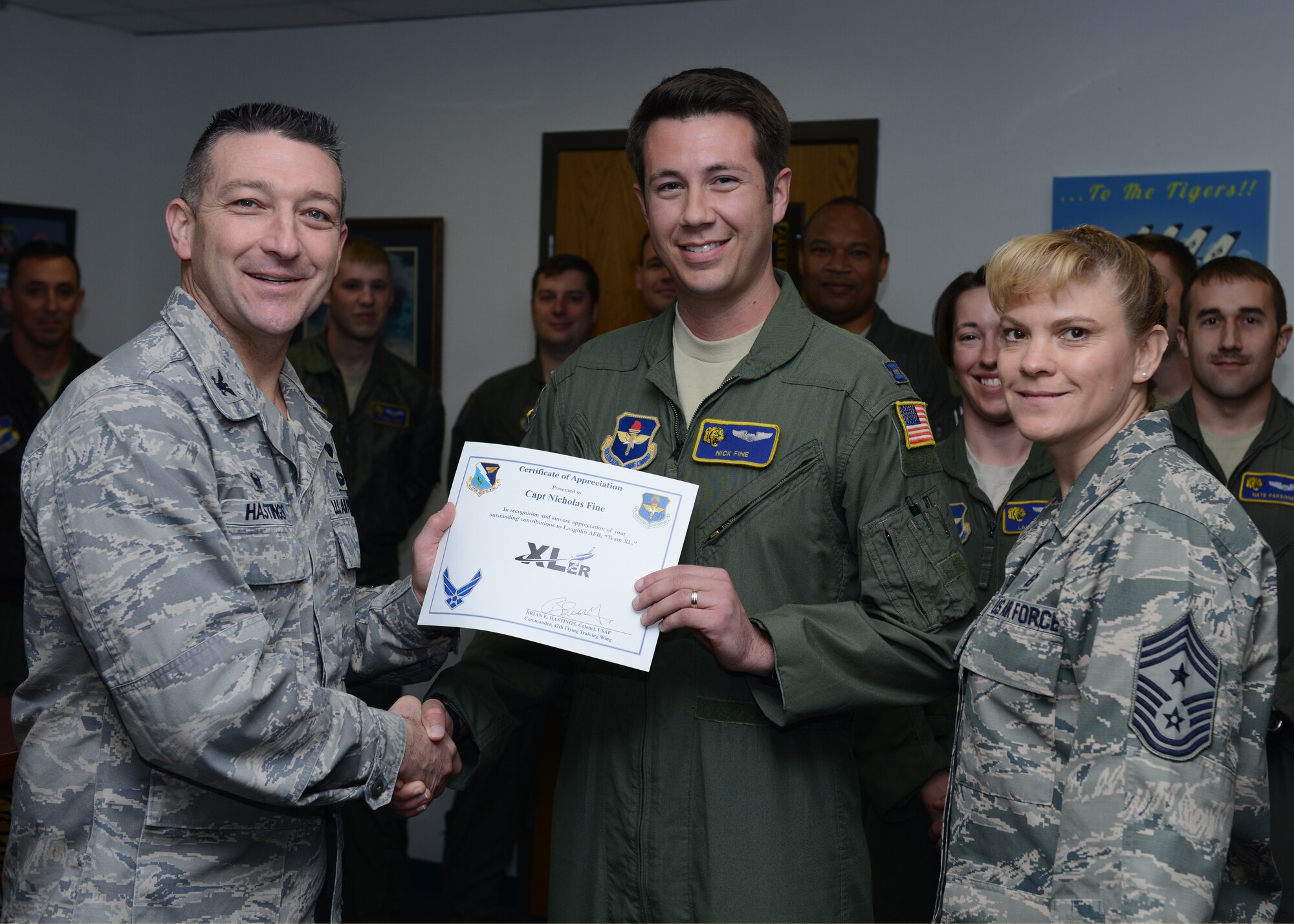 Capt. Nicholas Fine, center, 85th Flying Training Squadron F-flight assistant commander, poses with Col. Brian Hastings, left, 47th Flying Training Wing commander, and Chief Master Sgt. Teresa Clapper, right, 47th FTW command chief, after accepting the XLer of the week award here Feb. 17, 2015. The XLer is a weekly award chosen by wing leadership and is presented to those who consistently make outstanding contributions to their unit and Laughlin. (U.S. Air Force photo by Airman 1st Class Jimmie D. Pike)(Released)