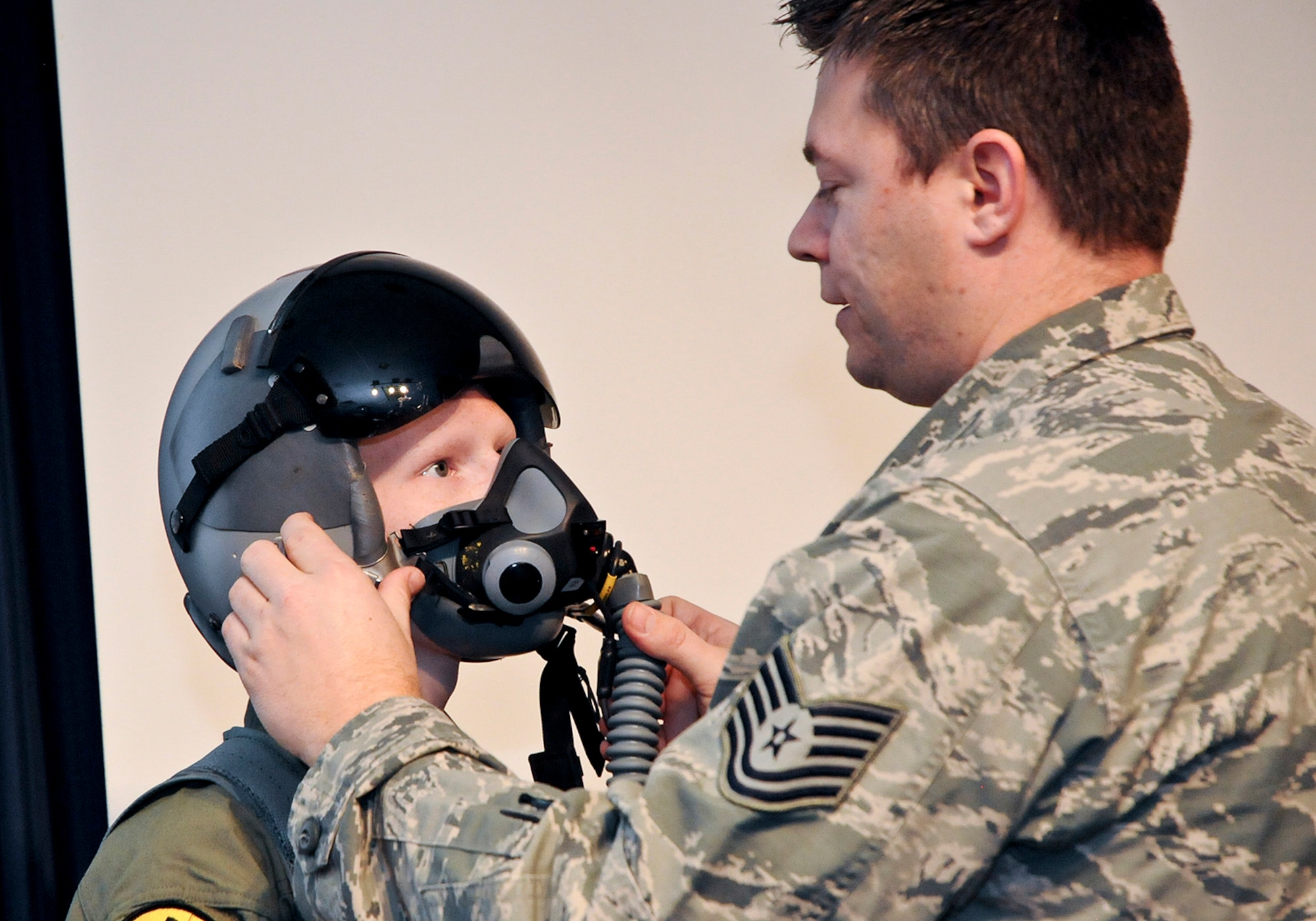 Aircrew Flight Equipment Technician, Tech. Sgt. Craig Michael adjusts a helmet for an honored guest of the 138th Fighter Wing and "pilot for a day" Josh Payton Feb. 19, 2015, at the Tulsa Air National Guard base, Tulsa, Okla.  The pilot for a day program is intended to recognize and honor children with potentially life threatening illnesses and started at the 138th in May 2012, and has hosted seven children since it began.  (U.S. National Guard photo by Senior Master Sgt.  Preston L. Chasteen/Released)