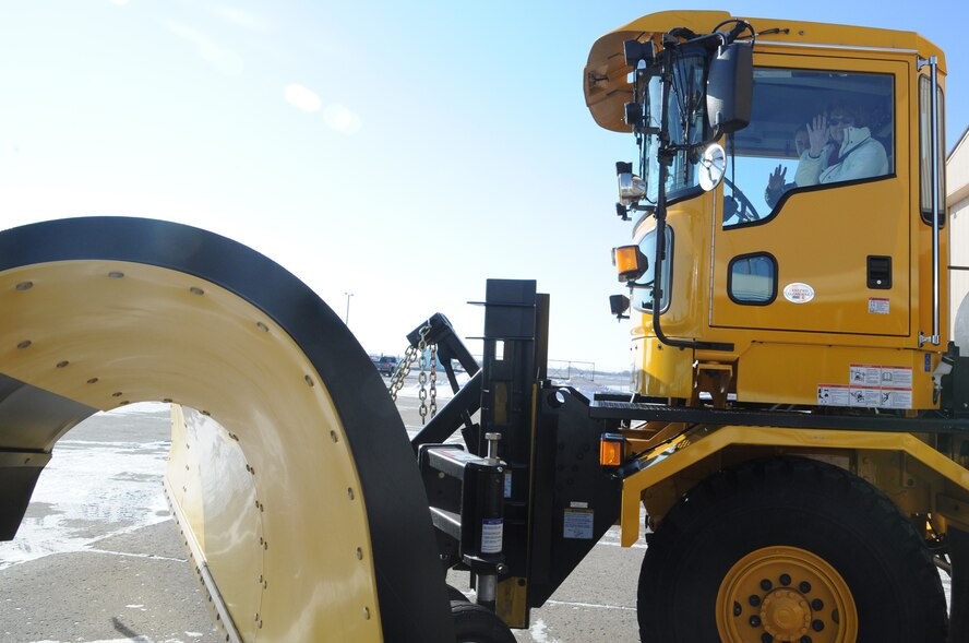 Kathleen Ferguson, principal deputy assistant secretary of the Air Force for installations, environment and energy, waves as she goes out for spin in a snowplow used to clear the runway on Grand Forks Air Force Base, N.D., Feb. 18, 2015. With Ferguson is Airman 1st Class Dylan Harrison, 319th CES pavements & equipment journeyman, who demonstrated snow removal operations. (U.S. Air Force photo/Staff Sgt. David Dobrydney)