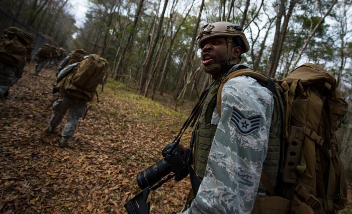 Staff Sgt. Jamal Sutter, 1st Combat Camera Squadron combat photojournalist, warns his team about an obstacle on the trail during a 2.2 mile ruck march at Joint Base Charleston, S.C., Jan. 29, 2015. The ruck march was conducted in preparation for their annual validation exercise which evaluates their ability to survive and operate in an austere environment. This ruck was dedicated to former 1 CTCS commander, Col. Aaron Burgstein, who passed away Jan. 27, 2015. Burgstein commanded the squadron from July 2009 to July 2012. (U.S. Air Force photo by Senior Airman Marianique Santos/Released)