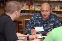 U.S. Navy Lieutenant Andrew Allison, the Offutt Volunteer Tutors program coordinator, tutors Bellevue East High School junior Jake Moore at the Bellevue, Neb. Public Library Jan. 27. The tutoring program provides free tutors to middle school, high school and college students. Allison is assigned to U.S. Strategic Command, Offutt Air Force Base, Neb. (U.S. Air Force photo by Delanie Stafford/Released)