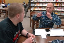 U.S. Navy Lieutenant Andrew Allison, the Offutt Volunteer Tutors program coordinator, tutors Bellevue East High School junior Jake Moore at the Bellevue, Neb. Public Library Jan. 27. The tutoring program provides free tutors to middle school, high school and college students. Allison is assigned to U.S. Strategic Command, Offutt Air Force Base, Neb. (U.S. Air Force photo by Delanie Stafford/Released)