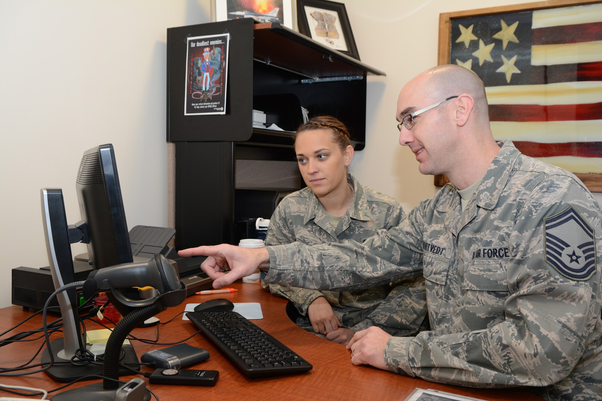 Senior Master Sgt. Craig A. Mortvedt, personnel superintendent for the Wisconsin Air National Guard's 115th Fighter Wing in Madison, Wis. instructs Senior Airman Amanda Lafke on the use of the Defense Enrollment Eligibility Reporting System Feb.8, 2015.(U.S. Air National Guard photo by Tech. Sgt.Tiffany Black)