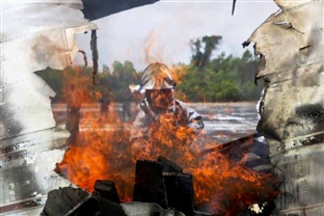 U.S. Marine Corps Cpl. Justin Groom stokes the fire inside a scrap airplane during exercise Cobra Gold 2015 on a Thai navy airfield about 90 miles southeast of Bangkok, Feb 18, 2015. Groom is an aircraft rescue firefighter assigned to Marine Wing Support Squadron 172, 1st Marine Aircraft Wing.