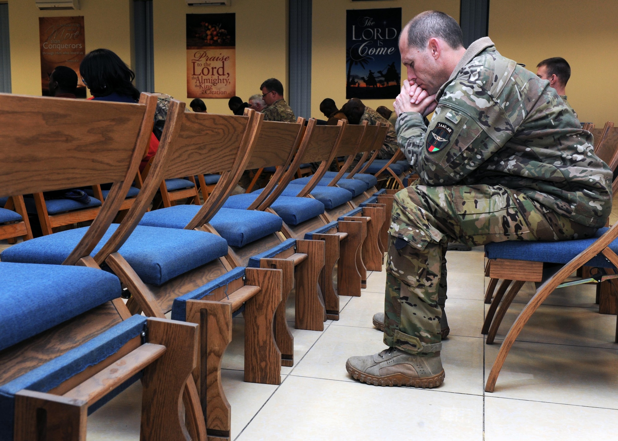 A U.S. Air Force Airman assigned to the 438th Air Expeditionary Wing bows his head in prayer during an evening church service conducted by U.S. Air Force Maj. William Braswell, 455th Air Expeditionary Wing chaplain, Feb. 15, 2015 at Hamid Karzai International Airport in Kabul. Braswell, accompanied by U.S. Air Force Tech. Sgt. Aleric Hebert, 455 AEW chaplain assistant, travels throughout the U.S. Air Force Central Command Area of Responsibility engaging with Airmen and conducting church services to ensure deployed servicemembers are spiritually fit to fight.(U.S. Air Force photo by Staff Sgt. Whitney Amstutz/released)