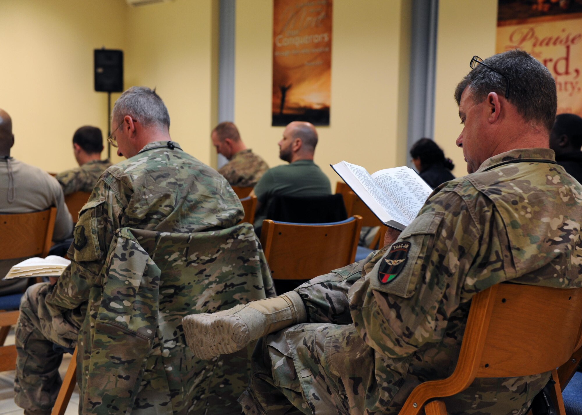 U.S. Air Force Airmen assigned to the 438th Air Expeditionary Wing read along during an evening church service conducted by U.S. Air Force Maj. William Braswell, 455th Air Expeditionary Wing chaplain, Feb. 15, 2015 at Hamid Karzai International Airport in Kabul. Braswell, accompanied by U.S. Air Force Tech. Sgt. Aleric Hebert, 455 AEW chaplain assistant, travels throughout the U.S. Air Force Central Command Area of Responsibility engaging with Airmen and conducting church services to ensure deployed servicemembers are spiritually fit to fight.(U.S. Air Force photo by Staff Sgt. Whitney Amstutz/released)