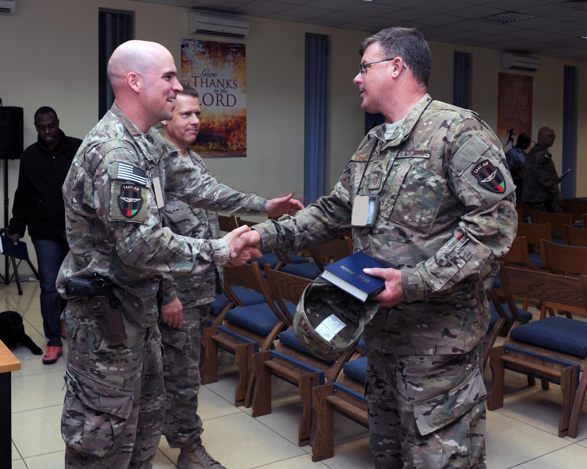 U.S. Air Force Tech. Sgt. Aleric Hebert, 455th Air Expeditionary Wing chaplain assistant, shakes hands with an Airman assigned to the 438th Air Expeditionary Wing following an evening church service conducted by U.S. Air Force Maj. William Braswell, 455 AEW chaplain, Feb. 15, 2015 at Hamid Karzai International Airport in Kabul. Hebert and Braswell travel throughout the U.S. Air Force Central Command Area of Responsibility engaging with Airmen and conducting church services to ensure deployed servicemembers are spiritually fit to fight.(U.S. Air Force photo by Staff Sgt. Whitney Amstutz/released)