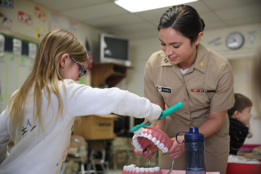 Lt. Michelle Romeo teaches a first-grade students proper brushing techniques during  National Children's Dental Health Month at Graham A. Barden Elementary School in Havelock N.C., Feb. 12, 2015. Romeo is a dentist with Naval Health Clinic Cherry Point, N.C., and a native of Charleston, W. Va.