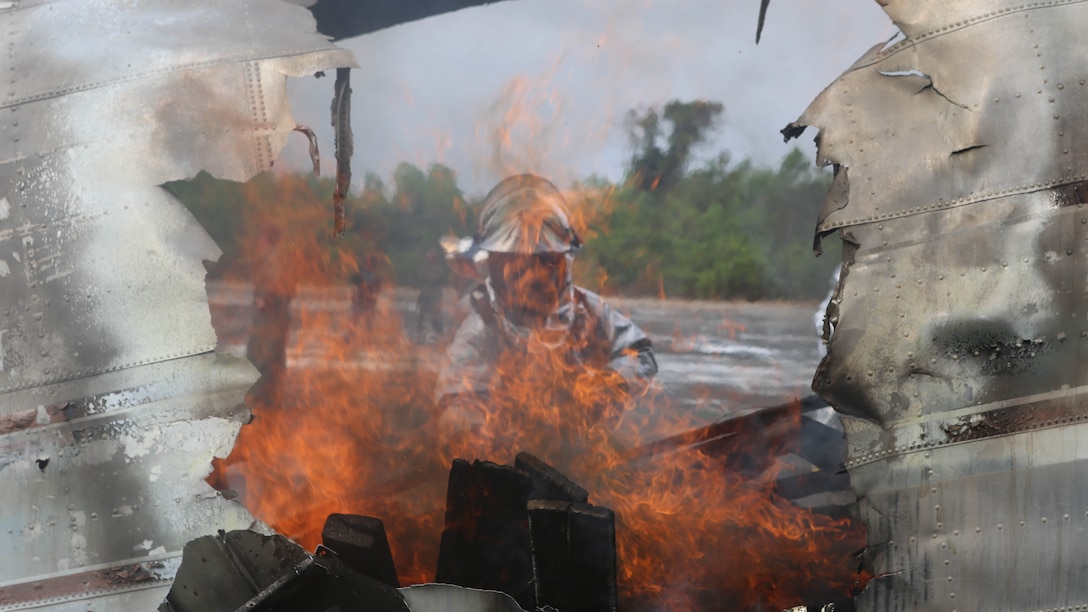Cpl. Justin Groom, an aircraft rescue firefighter with Marine Wing Support Squadron 172, 1st Marine Aircraft Wing, stokes the fire inside of a scrap airplane during a fire response scenario Feb 18, at Utapao Royal Thai Navy Airfield, Kingdom of Thailand. The scenario is part of exercise Cobra Gold 2015, which is designed to improve international partnerships and security within the region. 