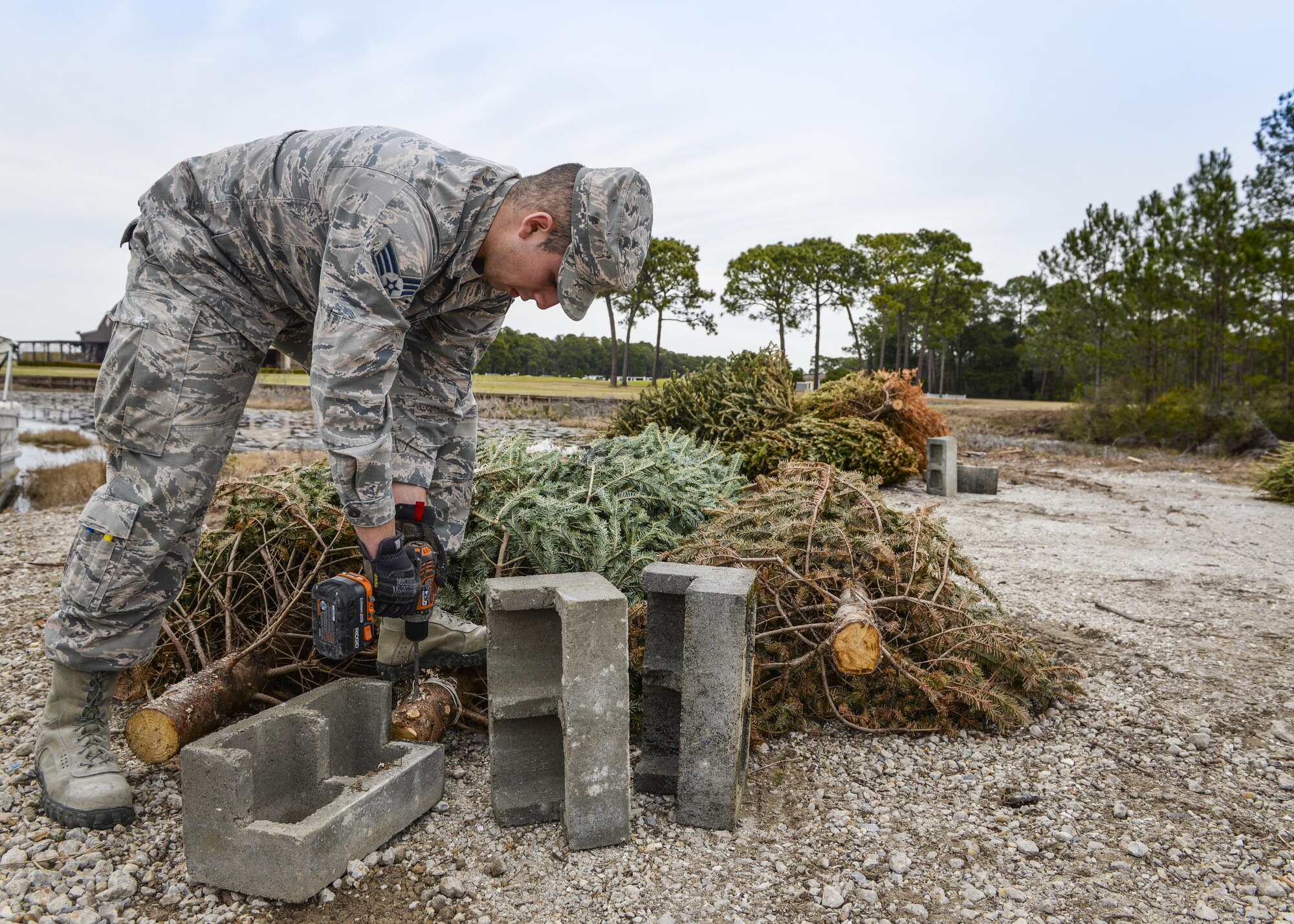 Senior Airman Raul Pedroza, 1st Special Operations Civil Engineer Squadron structural apprentice, prepares discarded Christmas trees for recycling at Hurlburt Field, Fla., Feb. 3, 2015. In order to utilize Hurlburt resources effectively, the trees are sunk to the bottom of Gator Lake, providing a suitable habitat for marine life. (U.S. Air Force photo by Senior Airman Meagan Schutter/Released)