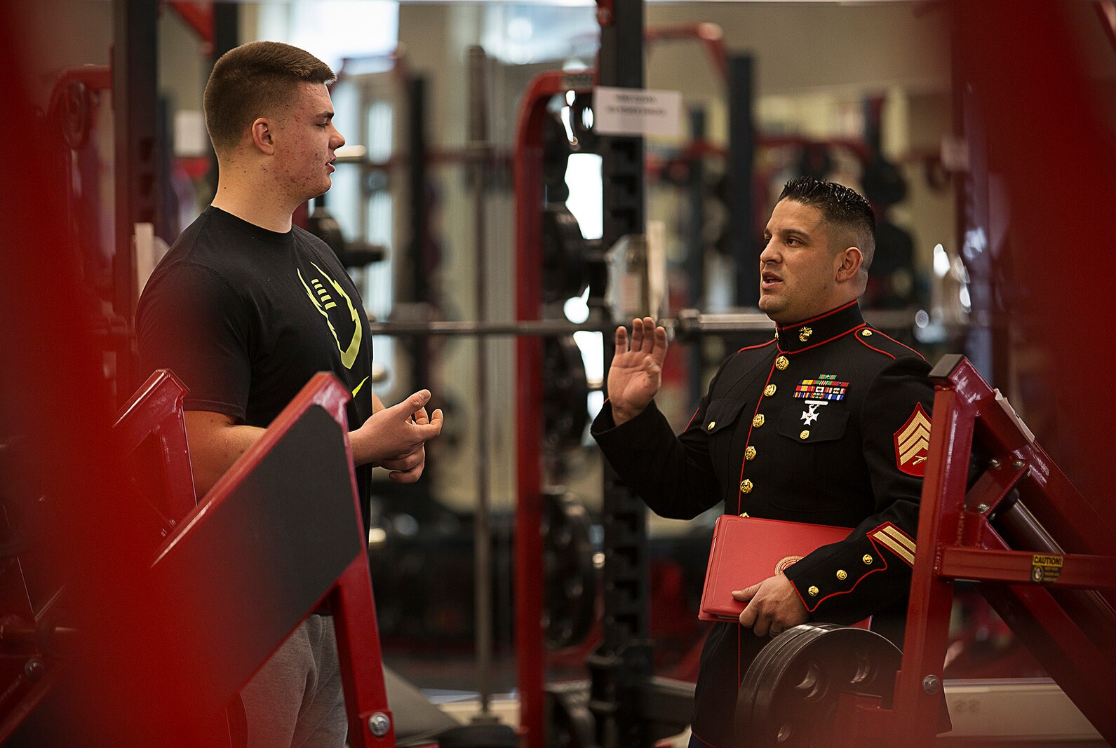 Shane Lemieux (left), a senior at West Valley High School in Yakima, Washington, speaks with local Marine recruiter Sgt. James Campos prior to receiving a Semper Fidelis All-American Bowl game certificate in the school's weight room Feb. 18, 2015. Lemieux, a highly-touted offensive guard, was one of three Washington State football players selected to play in the January 4 game in Carson, California. Following his high school graduation, Lemieux will attend the University of Oregon on an athletic scholarship. (U.S. Marine Corps photo by Sgt. Reece Lodder)