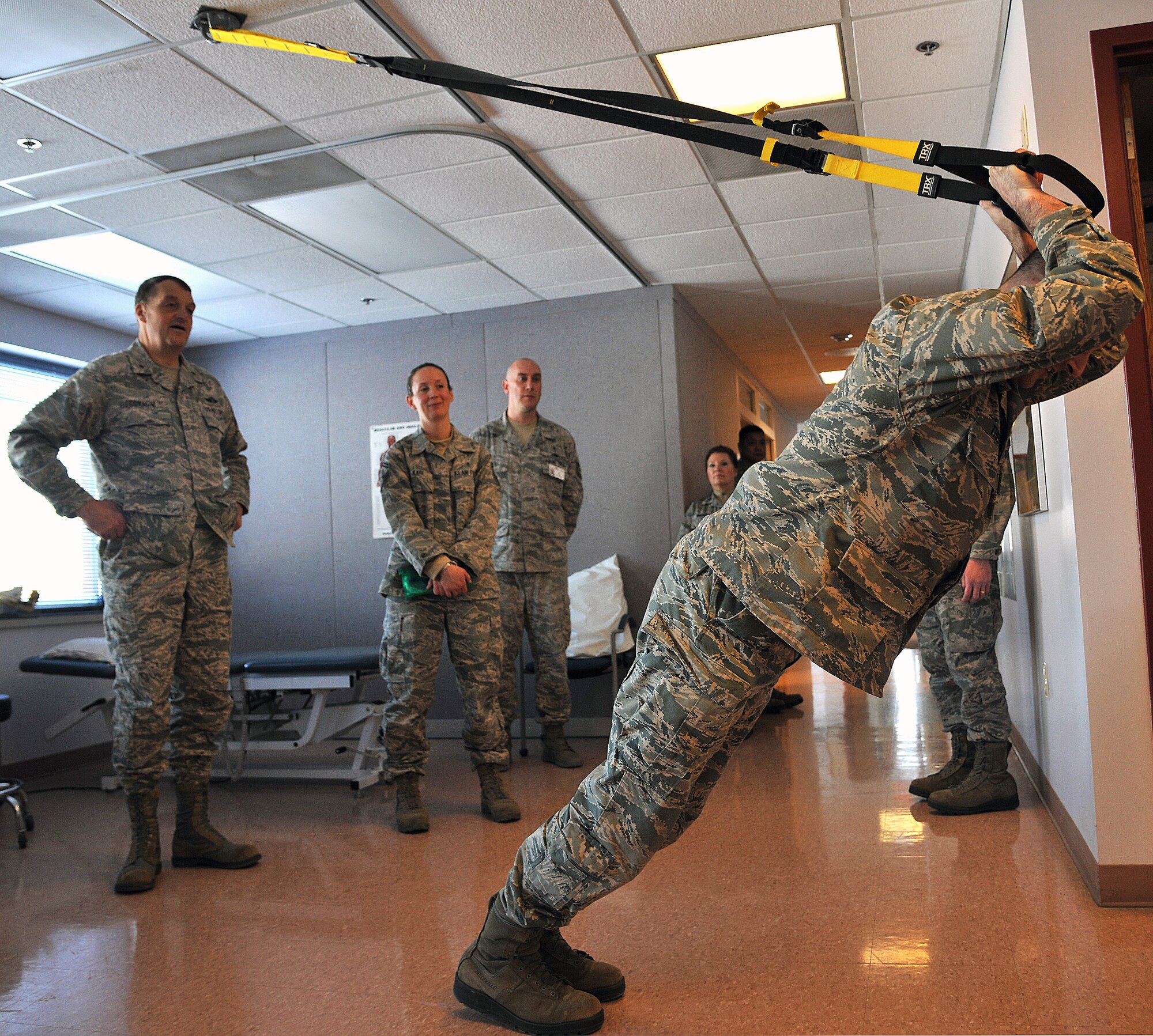 Brig. Gen. (Dr.) Kory Cornum, Air Mobility Command Surgeon and Senior Master Sgt. JoLynn Kari observes Maj. Justin Theiss, 319th Medical Group physical therapist, performing a triceps exercise on Feb. 19, 2015, at the 319th MDG clinic on Grand Forks Air Force Base, N.D. Cornum's visit several medical facilities including Mental Health and Bioenvironmental Engineering. (U.S. Air Force photo/Senior Airman Xavier Navarro)